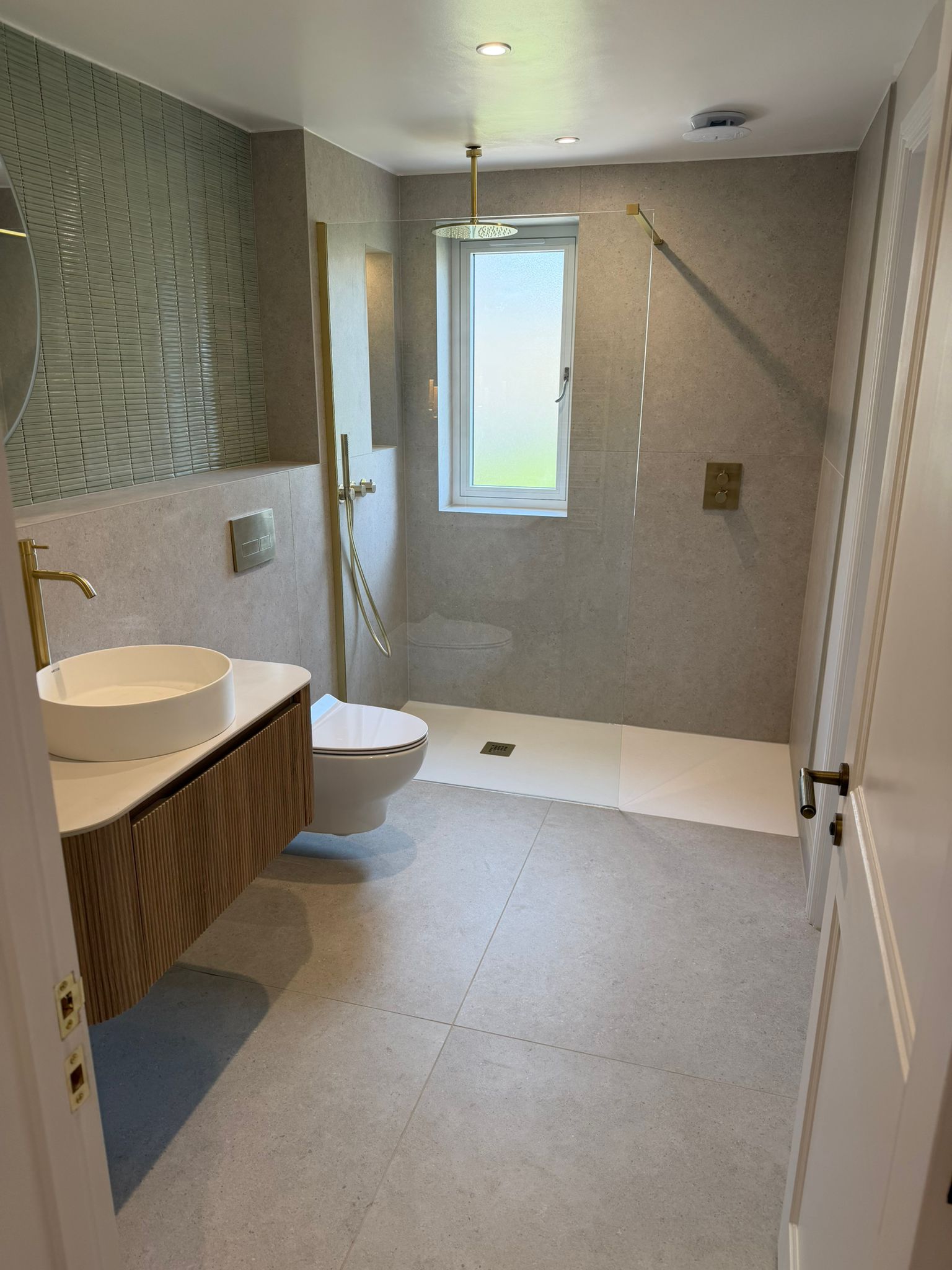 Compact pale stone bathroom with timber vanity and walk-in shower