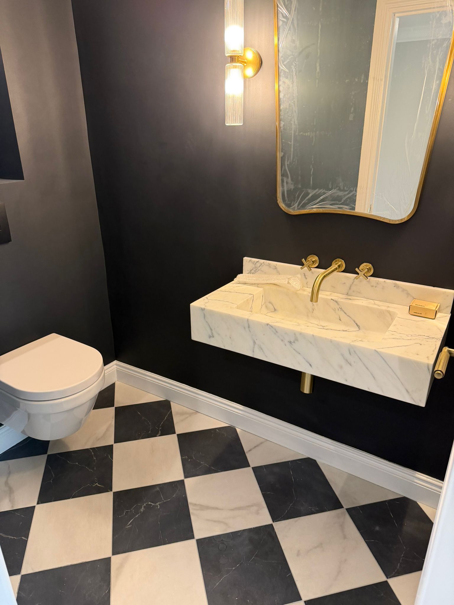 Cloakroom with black walls, chequered floor, and marble wall-mounted basin