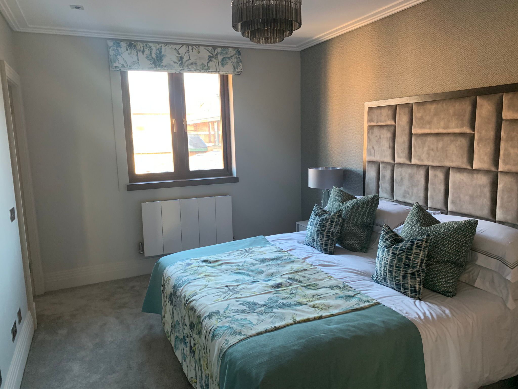 Finished bedroom with a patterned bedspread and dark-framed window