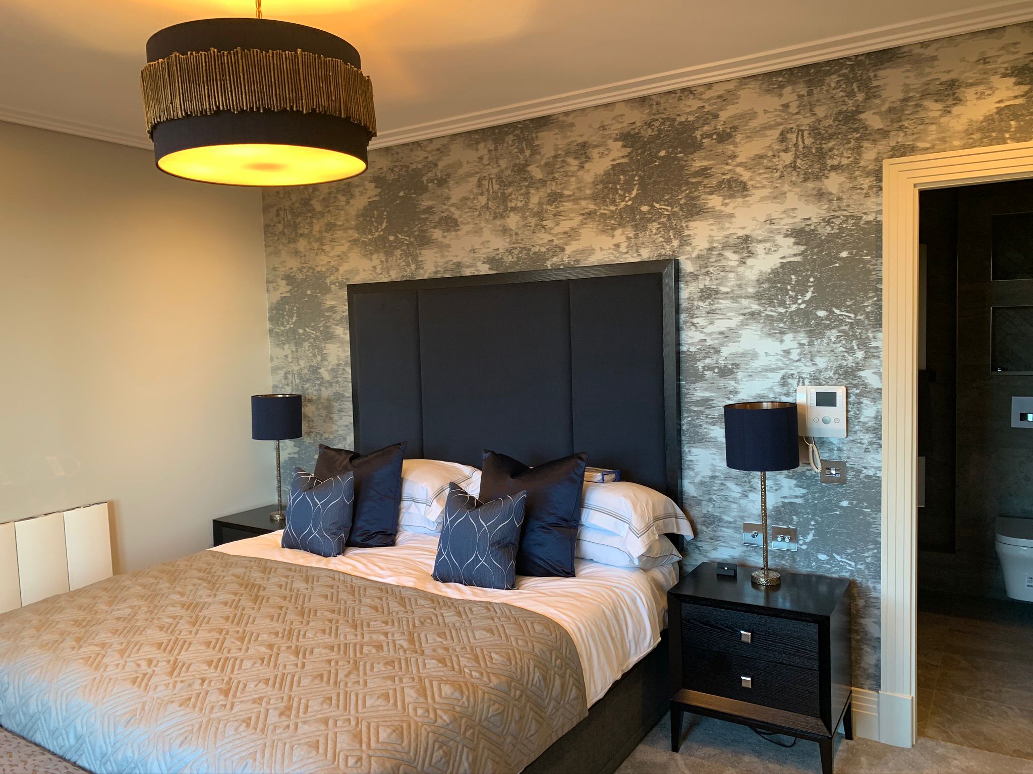 Bedroom with a dark upholstered bed against a textured feature wall