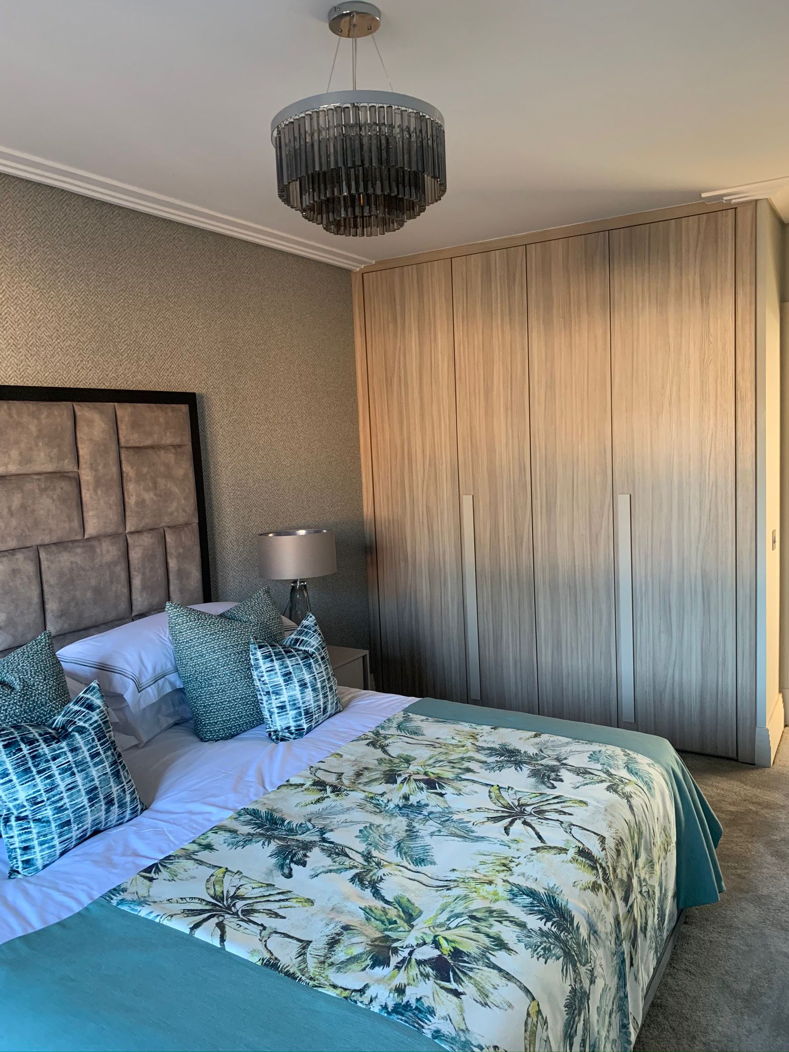 Bedroom with an upholstered headboard beside full-height fitted wardrobes