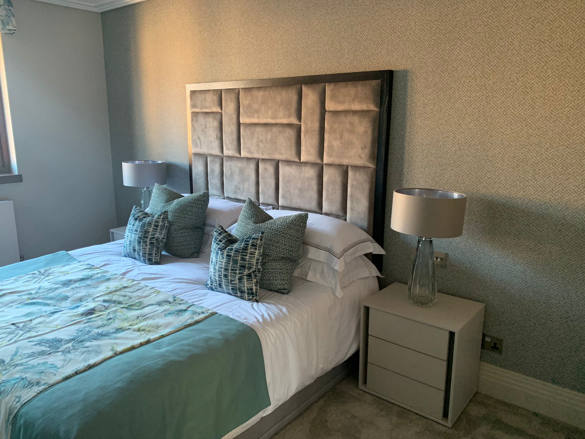 Finished bedroom with upholstered headboard, bedside cabinet, and wall covering