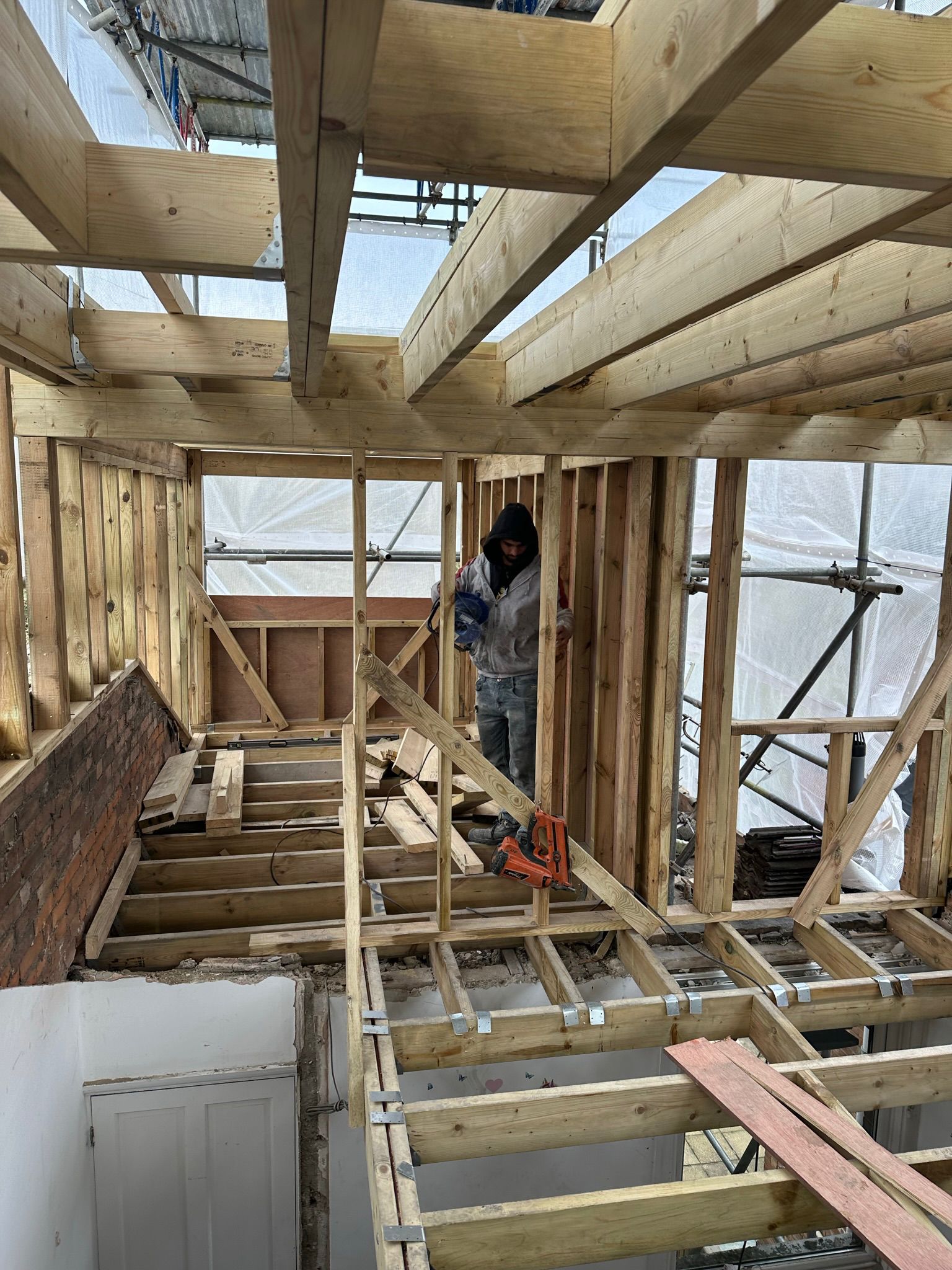 Timber upper-floor frame under construction inside scaffolding