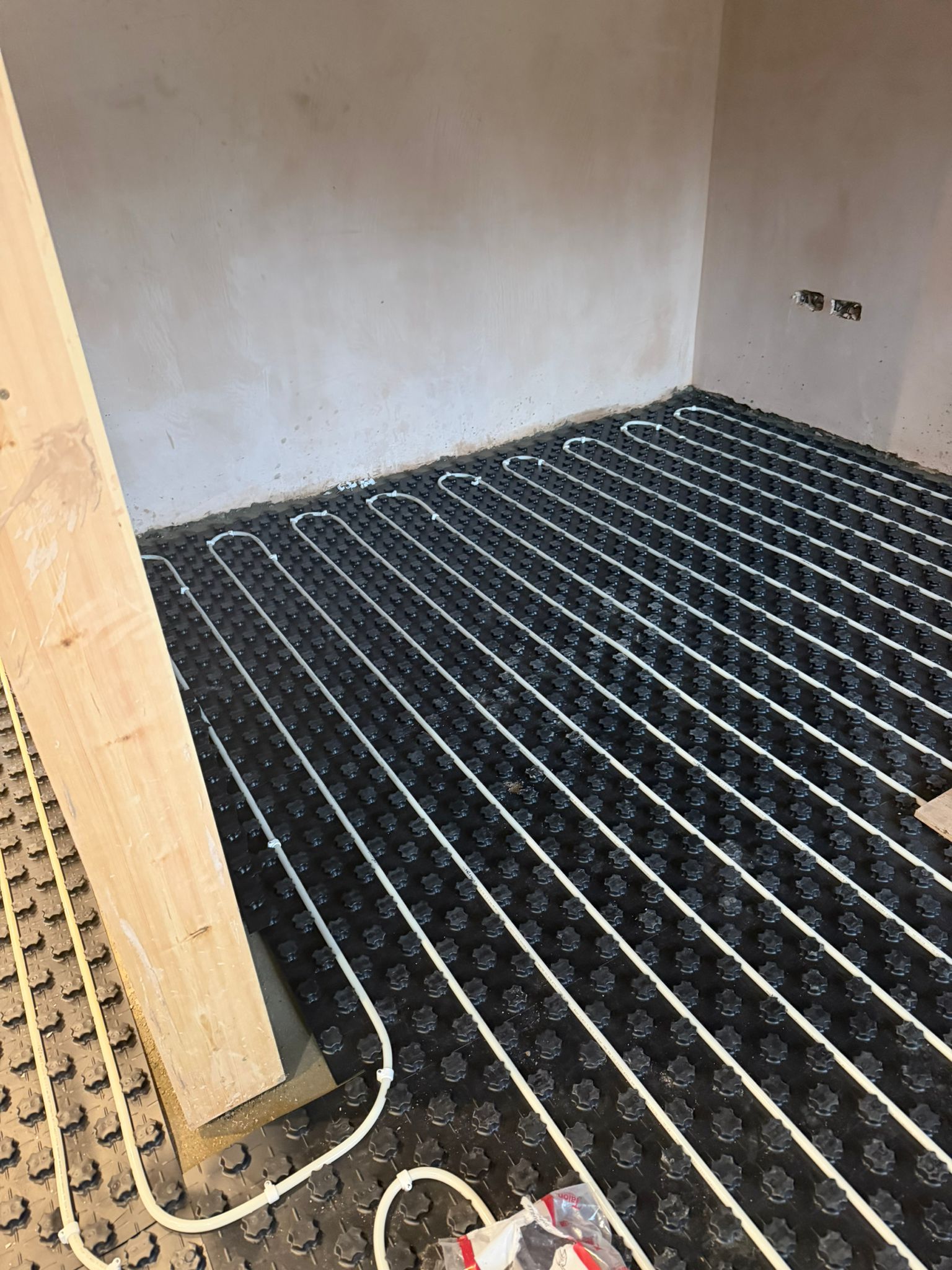 Underfloor heating pipes arranged across an unfinished floor