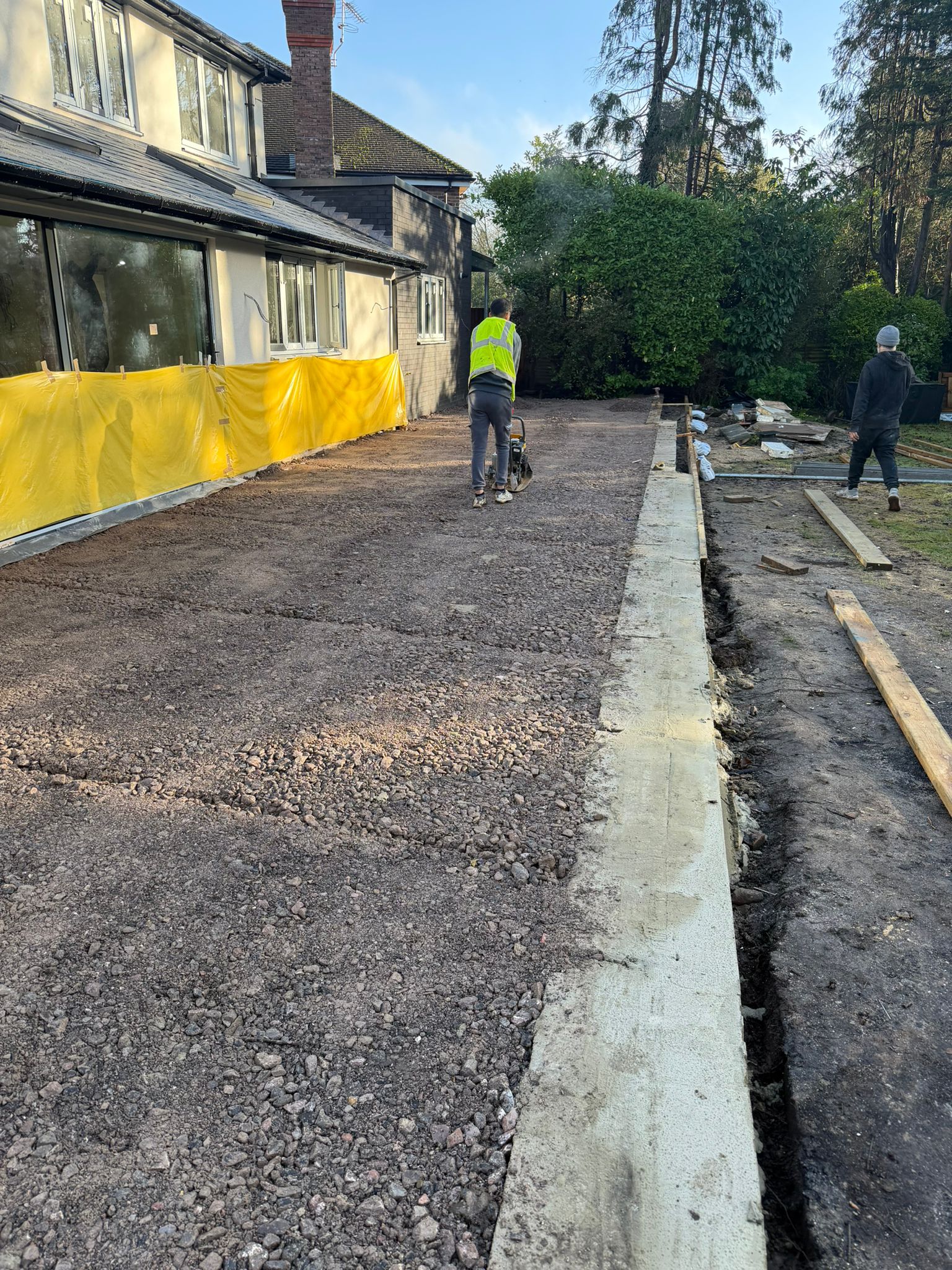 Driveway base and edging under construction beside a garden