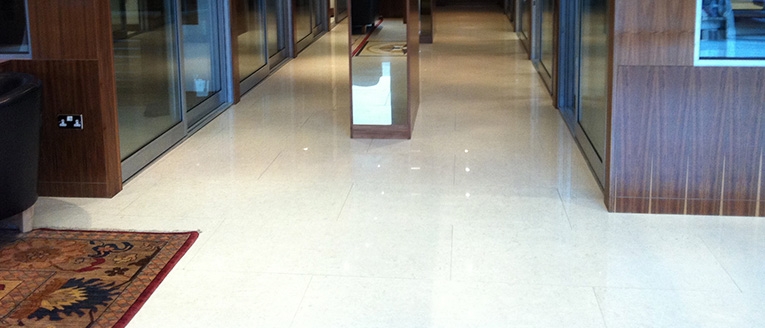 Polished pale stone floor along a glazed corridor