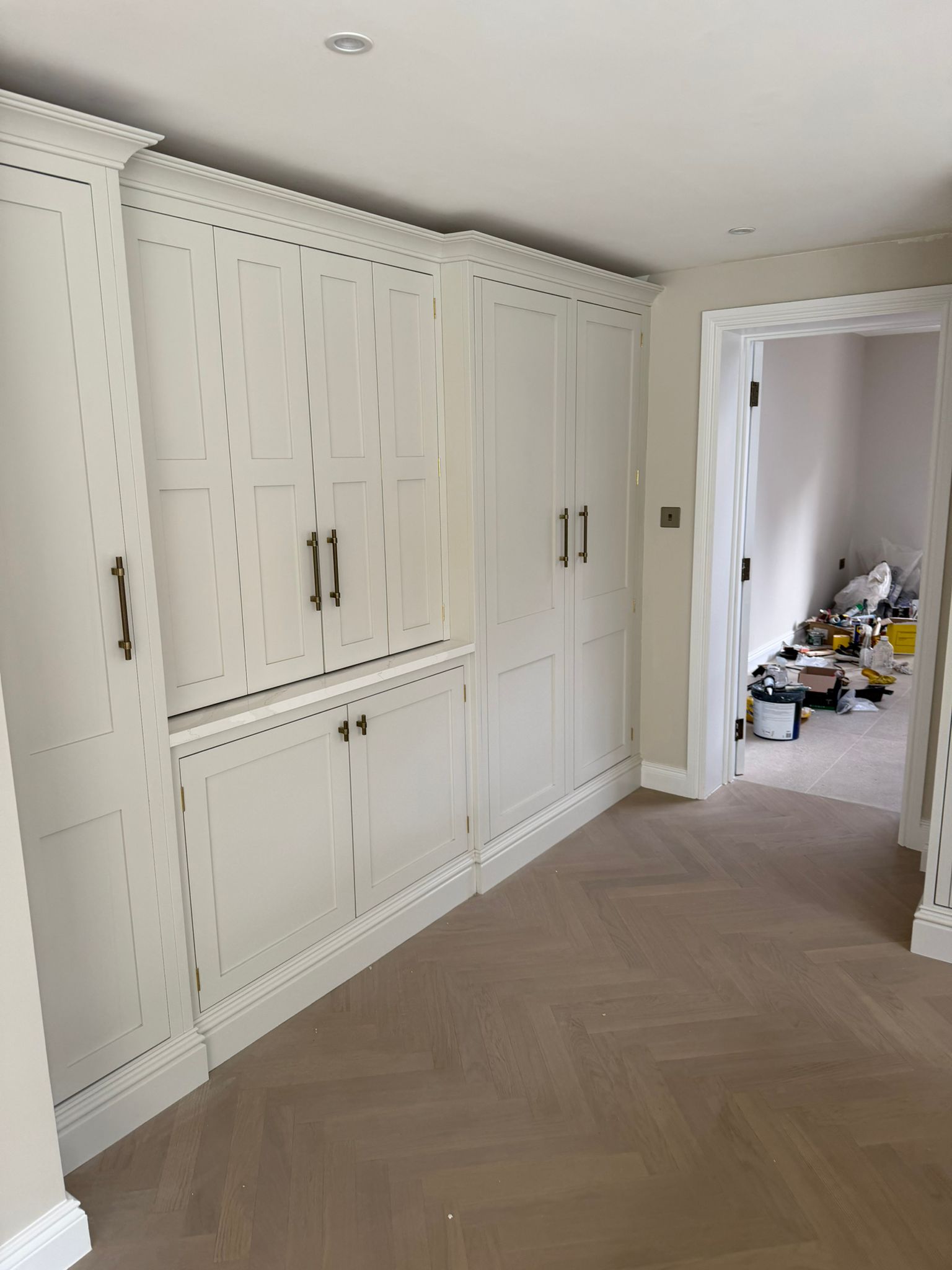 Pale herringbone floor fitted beside built-in hallway storage