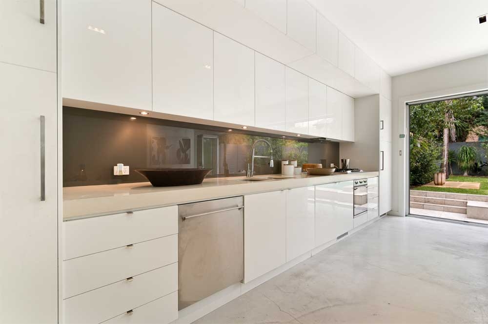 Minimal white kitchen with handleless cabinets and garden access