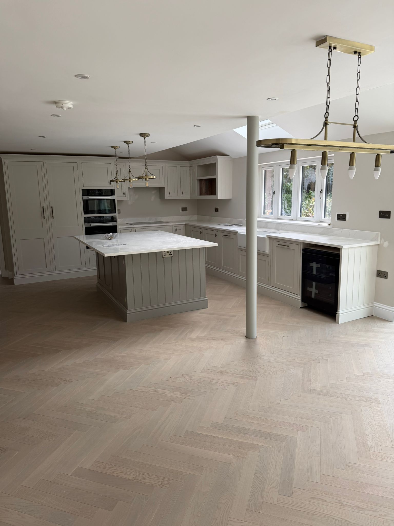 Pale shaker kitchen with island, tall cabinets, and rooflights