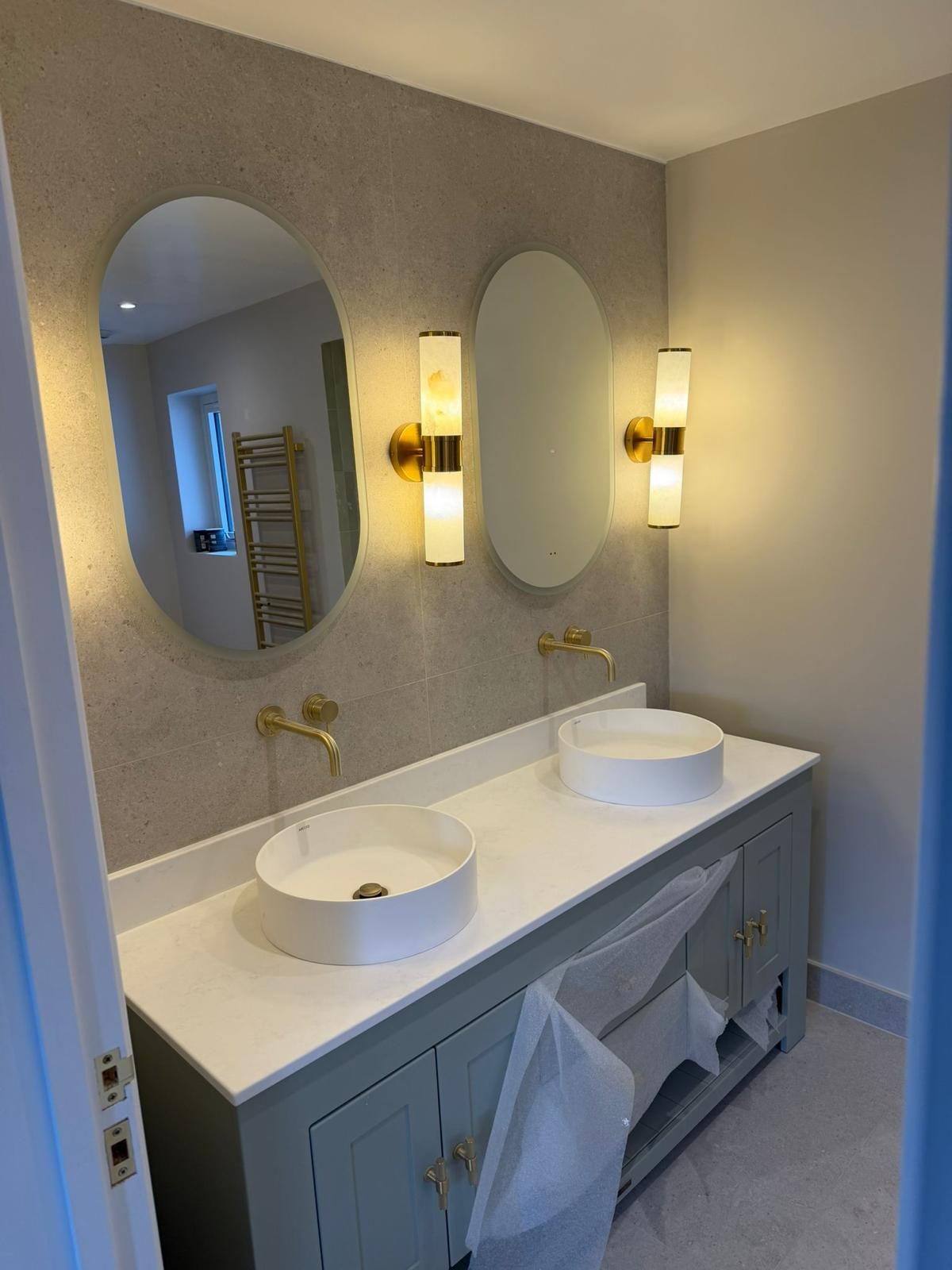 Double bathroom vanity with a pale stone top and matching wall finish
