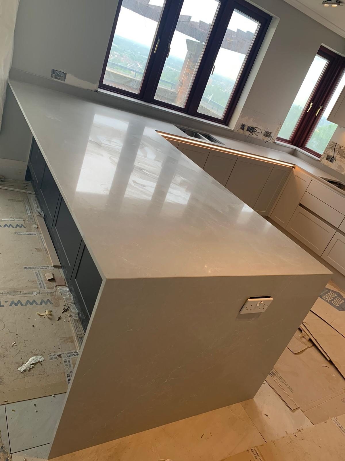 Stone kitchen worktops being installed around fitted cabinetry